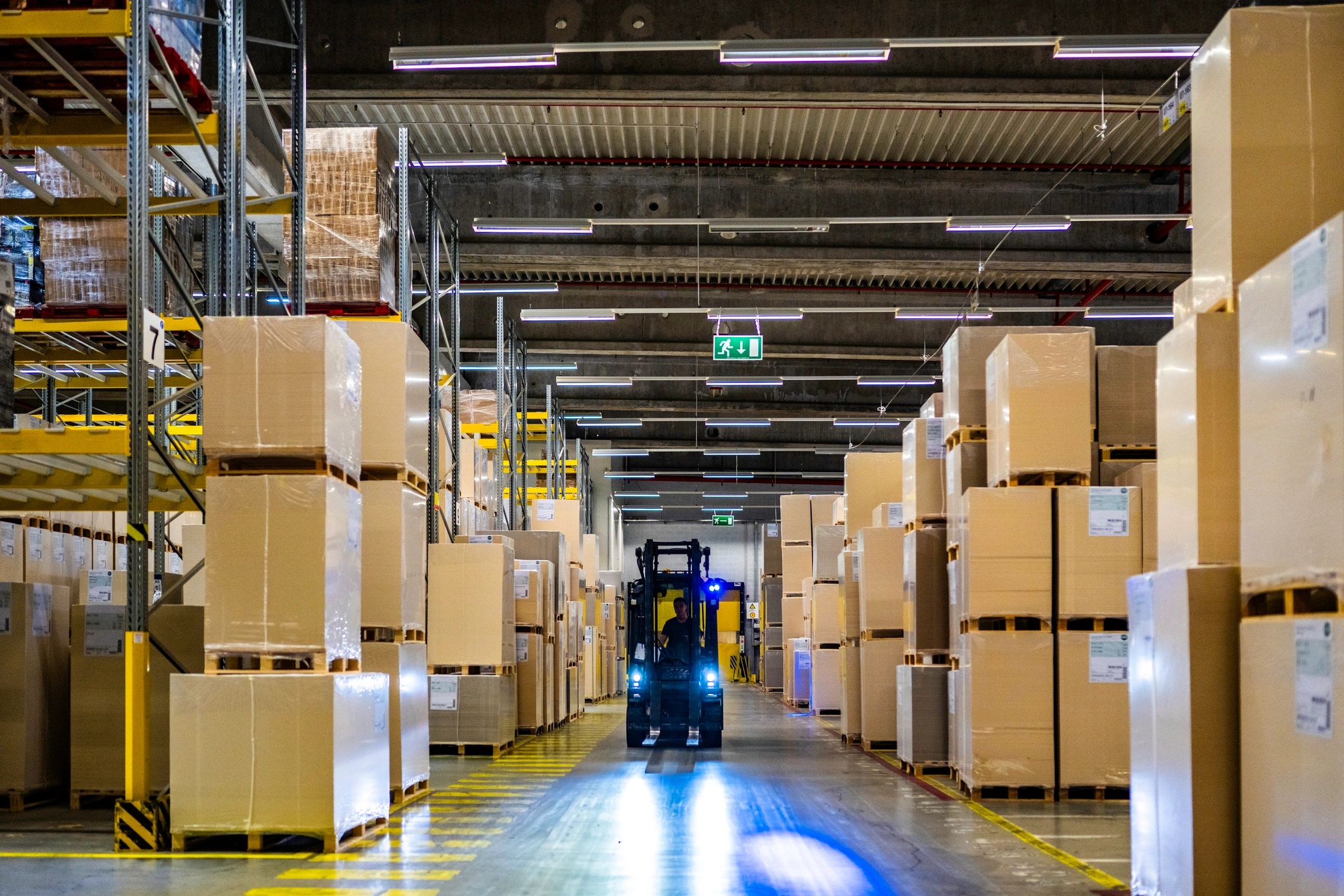 Forklift loading pallets in a warehouse aisle
