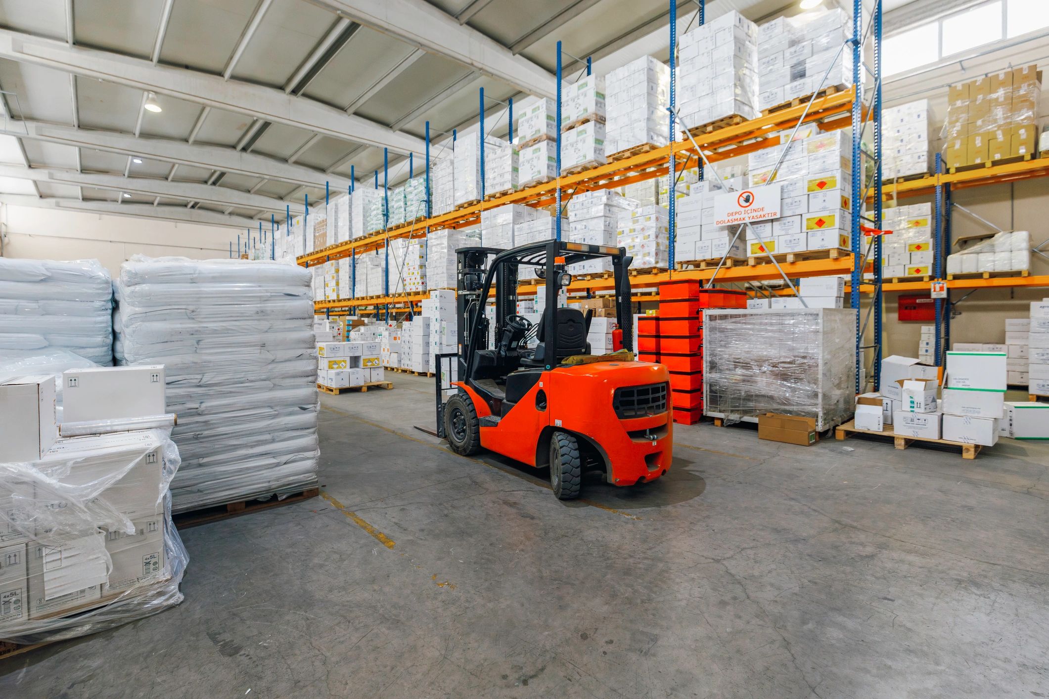 Forklift in a warehouse aisle with stacked pallets